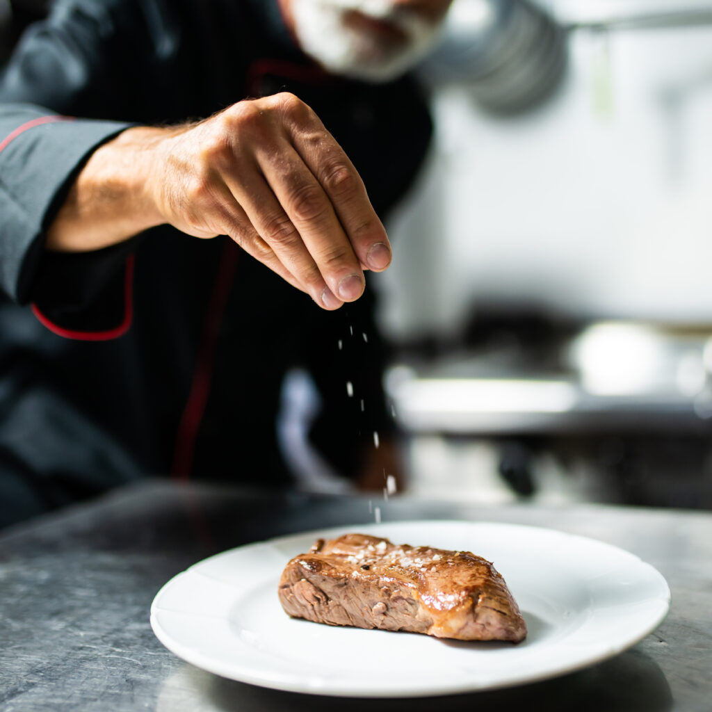 chef-seasoning-steak-professional-kitchen