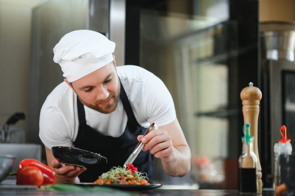 closeup-concentrated-male-chef-garnishing-food-kitchen